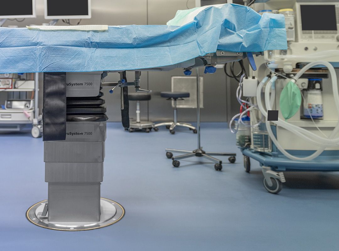 Operationstisch mit umherstehenden Gerätschaften im Krankenhaus und hygienischem Bodenbelag