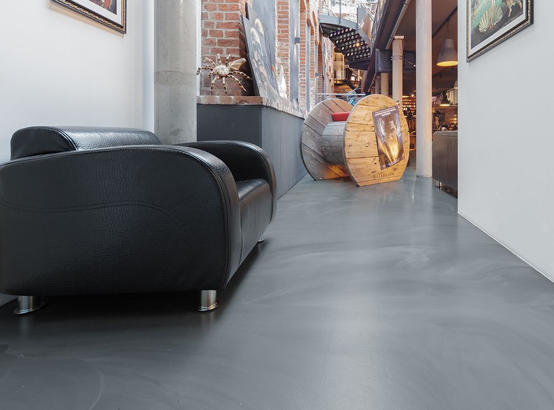 Schwarzes Sofa auf einem Fußboden in Wischtechnik in einem Tattoostudio