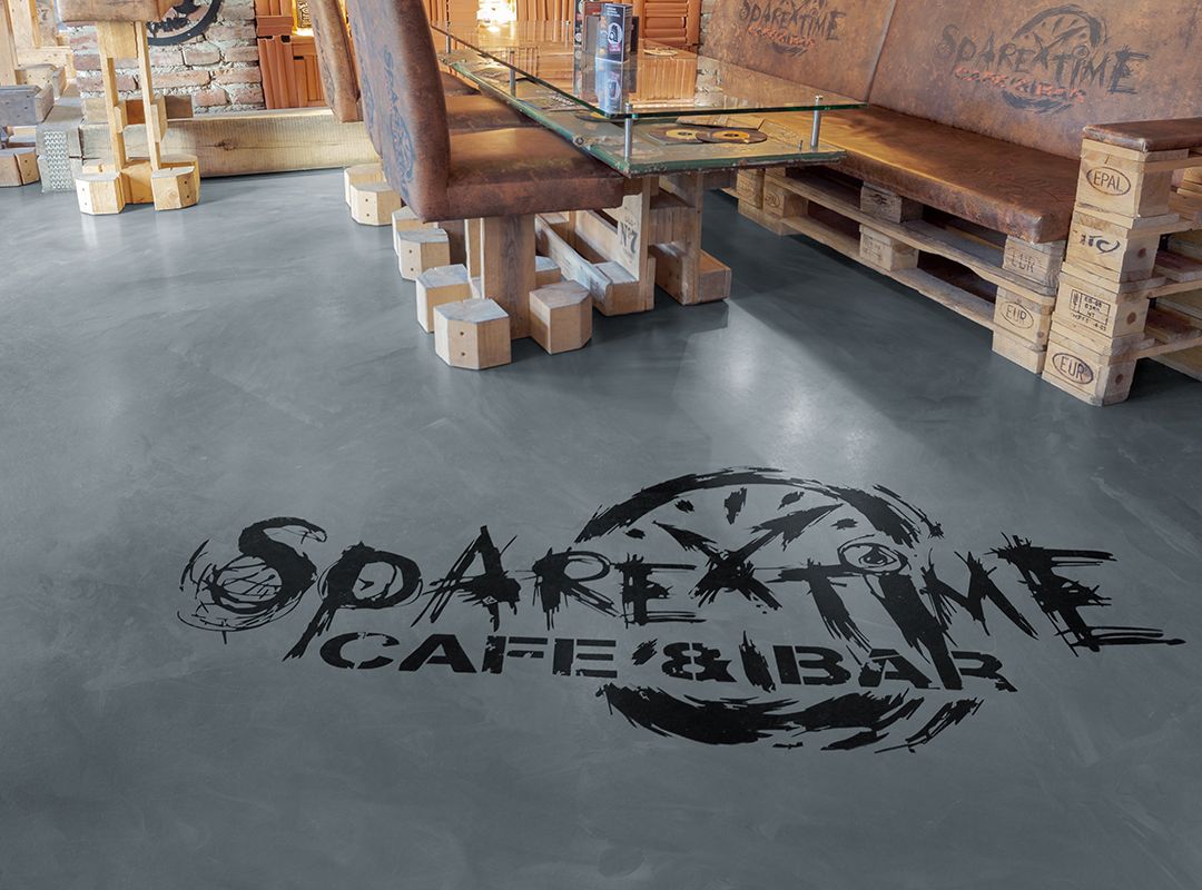 Eingearbeitetes Logo im Wischtechnik-Fußboden eines Tattoostudios mit einem Motorrad